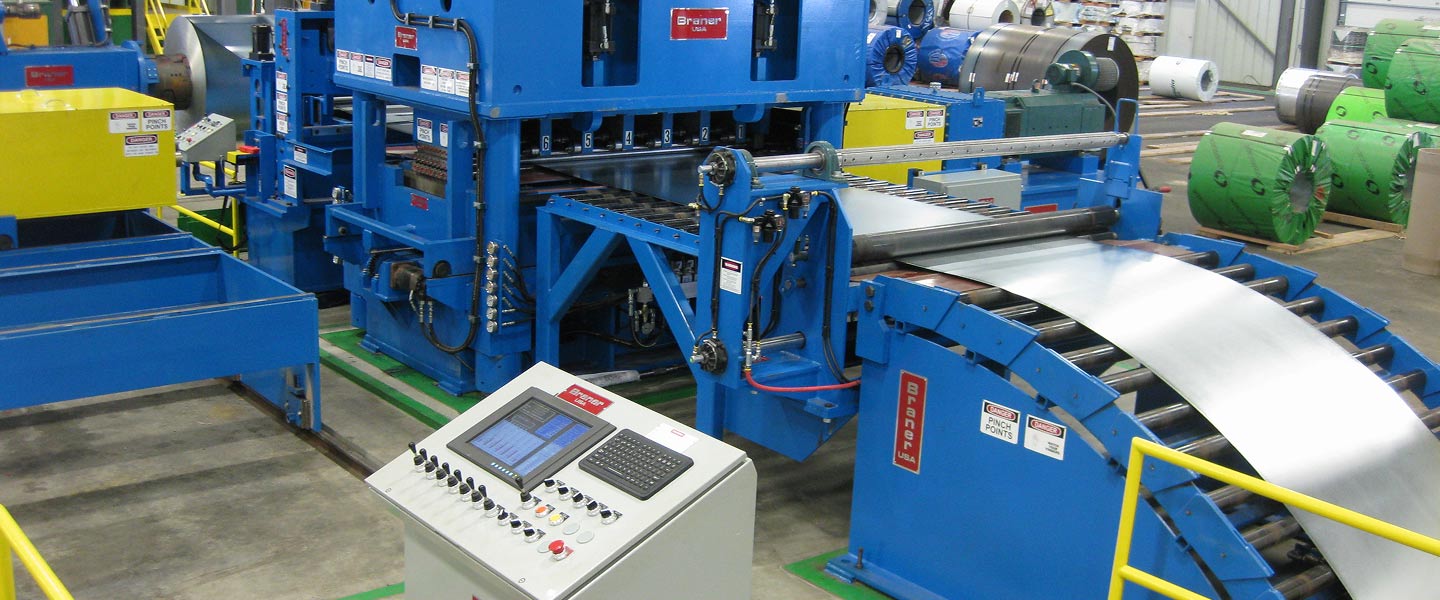 Close-up of automated metal slitting machine with control panel and conveyor system for precision sheet cutting